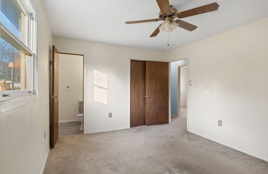 bedroom, closet, half bath doorway, ceiling fan, doorway to hallway