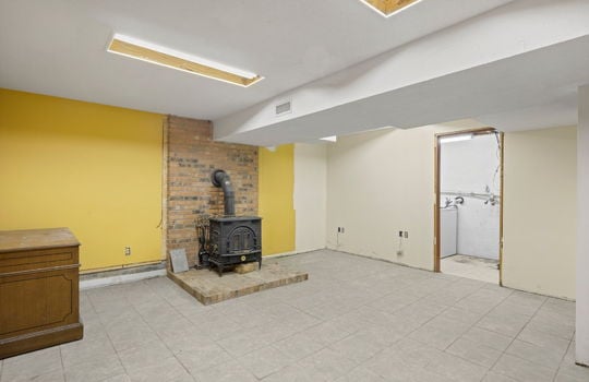 basement finished space, wood stove, doorway into laundry area, tile flooring
