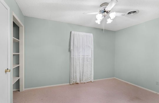 freshly painted bedroom, carpet, ceiling fan, built in shelving, closet