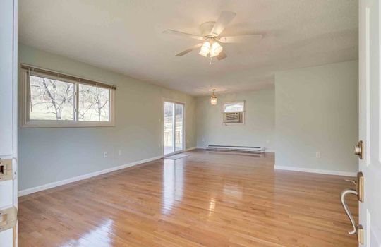 Living room, sliding glass door, ceiling fan, hardwood flooring, windows