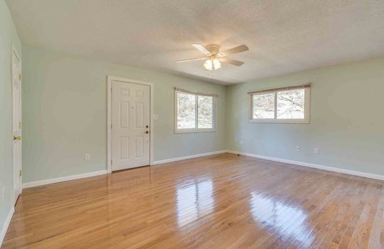 Living room, front door, hardwood flooring, ceiling fan, windows