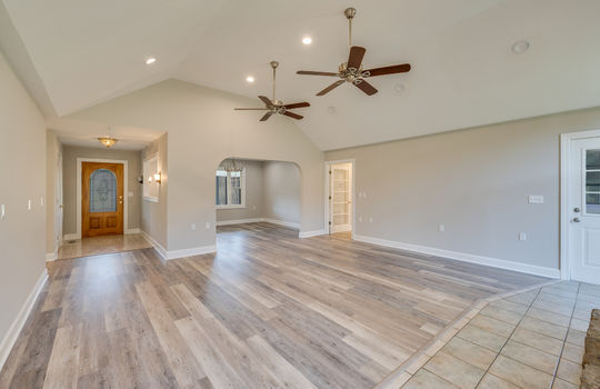 Living room, foyer, luxury vinyl plank flooring, ceiling fans, recessed lighting, view into dining area, hallway, hardwood flooring, tile flooring