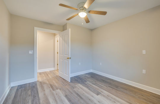 bedroom, luxury vinyl plank flooring, ceiling fan, door to hallway