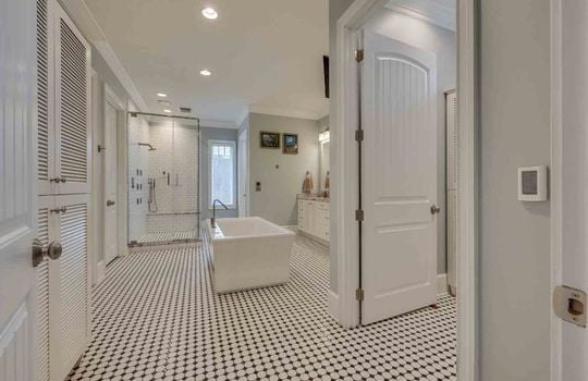 bathroom, soaker tub, tile shower with glass surround, large double sink vanity, tile flooring, watercloset door