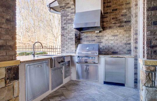 outdoor kitchen, outdoor grille, sink, tile flooring, brick exterior walls, outdoor countertops