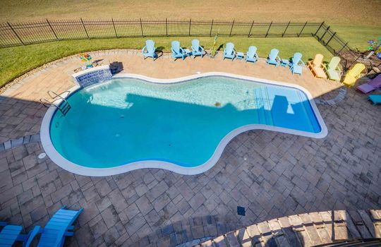 upper level view of in ground swimming pool, fenced yard, back yard, tile pool surround