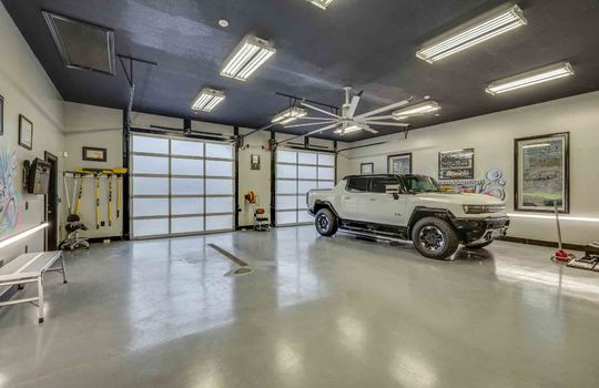 garage interior, garage doors, concrete flooring, flourescent lighting, ceiling fan,