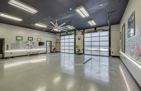 garage interior, garage doors, concrete flooring, flourescent lighting, ceiling fan,
