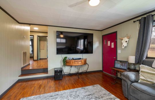 living room, hardwood flooring, front door, painted paneling walls, ceiling fan