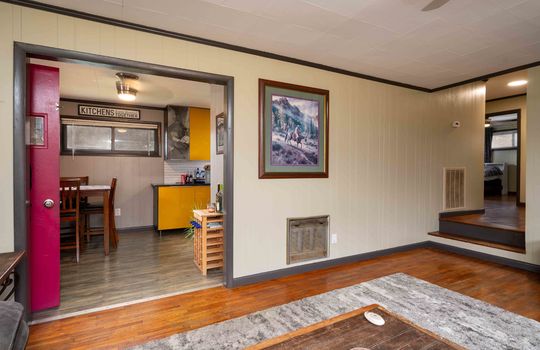 living room, view into kitchen/dining room, hardwood flooring, paneling walls