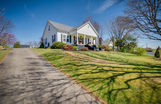 left side view, historic two level home, front steps, front door, front yard, landscaping, vinyl siding, asphalt driveway