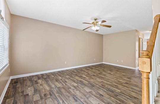 living room, luxury vinyl flooring, ceiling fan, stairs to upper level