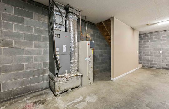 garage, cinderblock wall, concrete flooring, indoor heat pump unit, water heater