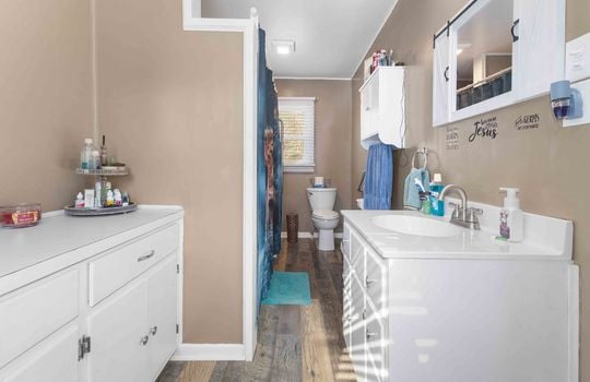 primary bath, sink, storage cabinets, toilet, shower/tub, luxury vinyl flooring