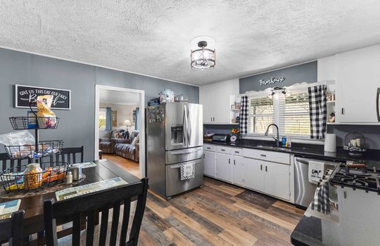 kitchen, luxury vinyl flooring, stainless dishwasher, stainless refrigerator, sink, window above sink, eat-in kitchen, doorway to living room
