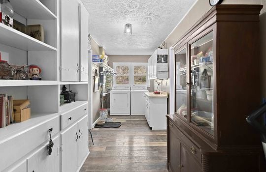 pantry leading to laundry space, cabinets, luxury vinyl flooring