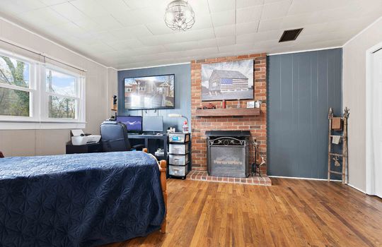 bedroom, brick fireplace, hardwood flooring