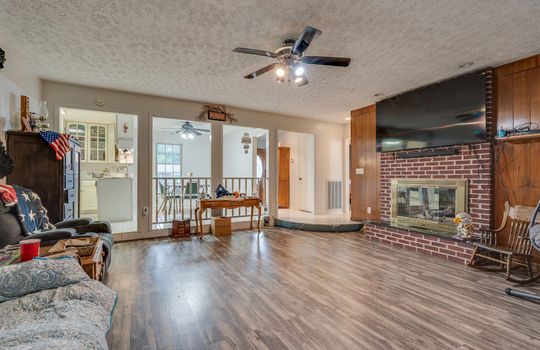 living room, vinyl flooring, fireplace, ceiling fan, view into kitchen/dining area