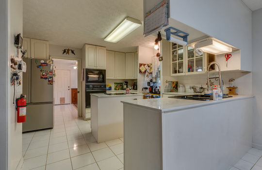 kitchen, tile flooring, island, built in oven, refrigerator, cooktop, cabinets, countertops, sink