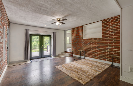 flex space with luxury vinyl flooring, brick feature wall, door access to back patio