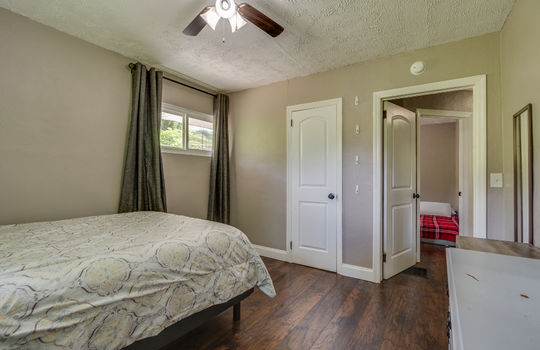 bedroom, doorway to hallway, luxury vinyl flooring, ceiling fan, half bath