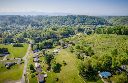 aerial view of property, road, driveway, double wide, back yard, fence, trees, landscaping, mountain views