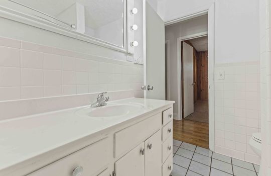 bathroom, cabinet, sink, vanity lighted mirror, tile flooring, door to hallway