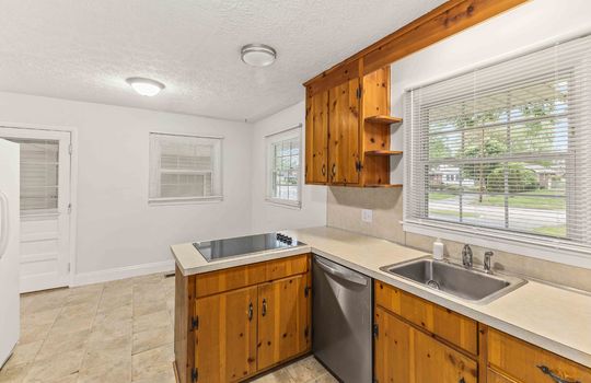 kitchen, dining area, cabinets, cooktop, dishwasher, sink, window above sink, vinyl flooring