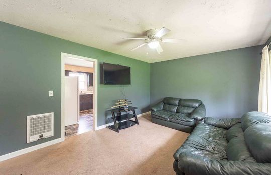 living room view from front door, carpet, ceiling fan, window, door to kitchen