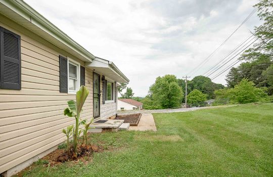 front left side view of home, landscaping, front door, storm door, vinyl siding, landscaping, front yard, sidewalk