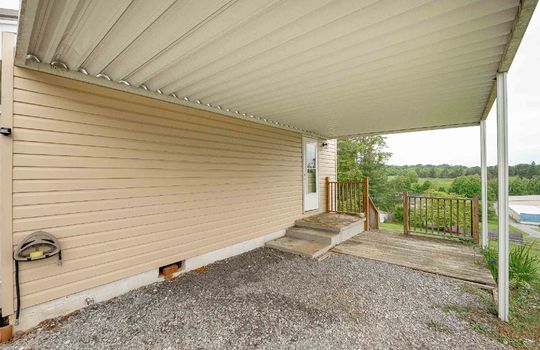 covered patio, gravel driveway, vinyl siding, exterior door