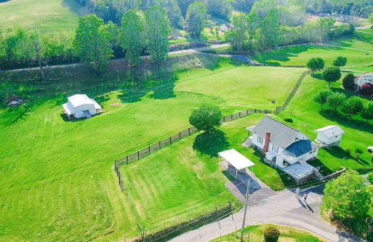aerial view of farmhouse, shed, and barn, 3+/- acres, yard, trees, mountain(s), field, driveway, carport, road