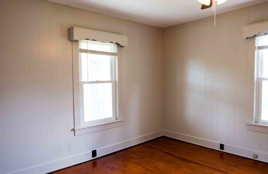 bedroom, painted paneling walls, hardwood flooring, decorative window framing, ceiling fan