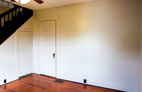 ceiling fan, hardwood flooring, painted paneling walls, storage closet, stairway