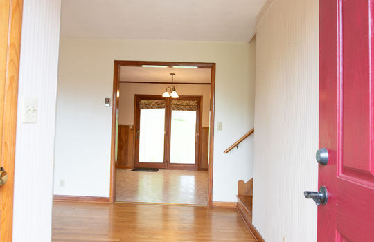 living room view through front door, front door, hardwood flooring, wood stairs, view into dining area.