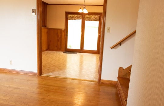 living room, hardwood flooring, wooden stairs, view into dining room, vinyl flooring