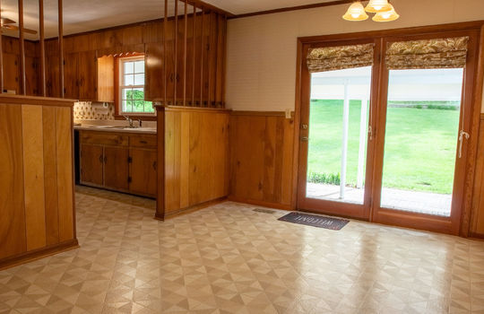 dining area, vinyl siding, view into kitchen, decorative partition, kitchen cabinets, door to back patio