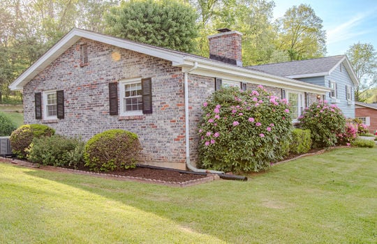 side view of home, tri-level, brick, vinyl siding, wood siding, landscaping, shrubs, front yard, side yard