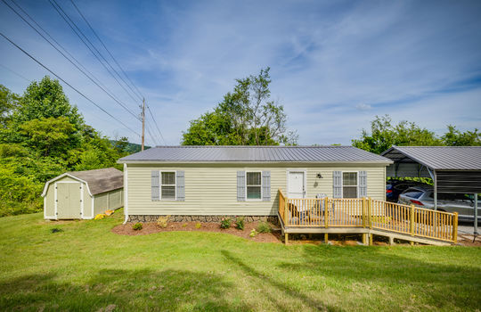 Double wide, manufactured home, front porch, ramp, front door, yard, carport, metal roof, vinyl siding, landscaping, storage shed