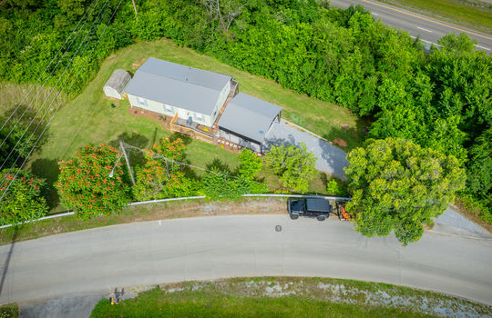 aerial view of home, carport, doublewide, metal roof, gravel drive, road, trees, front yard, back yard