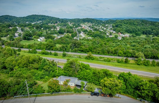 aerial view of home, carport, doublewide, metal roof, gravel drive, road, trees, front yard, back yard, neighborhood view