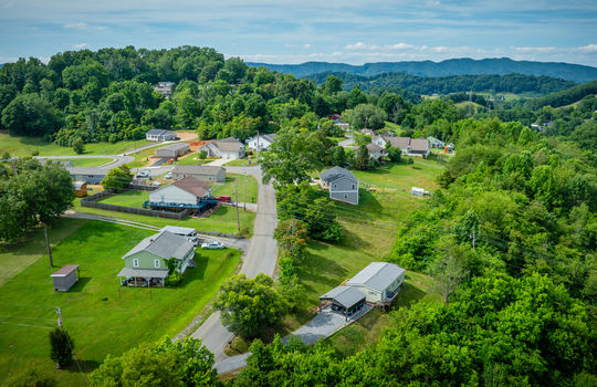 aerial view of home, carport, doublewide, metal roof, gravel drive, road, trees, front yard, back yard, neighborhood view