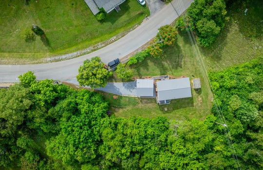 aerial view of home, carport, doublewide, metal roof, gravel drive, road, trees, front yard, back yard, neighborhood view