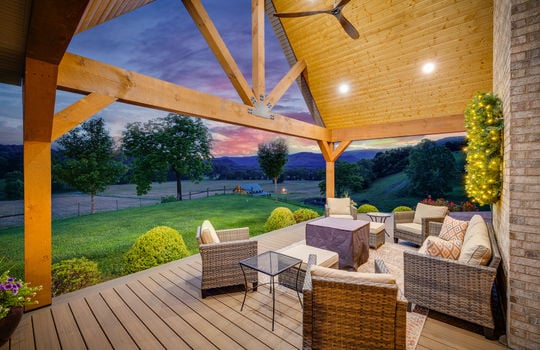 covered front porch, outdoor fan, recessed lighting, twilight view of front yard, landscaping, mountain views