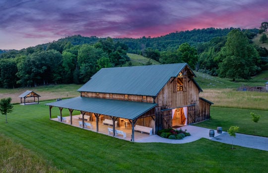 wedding/event venue, barn, porch, wood siding, metal roof, yard, trees, mountain views, twilight photo