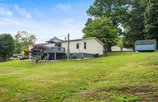 back right side view of double wide, back deck, yard, outdoor shed