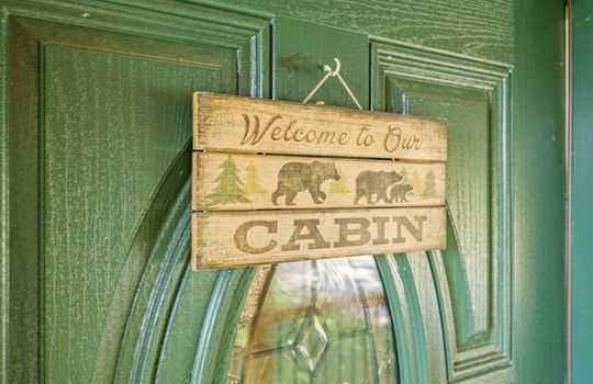 fully furnished log cabin, for lease only, front door sign reading "welcome to our cabin"