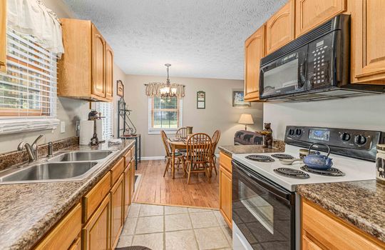 kitchen view into dining area, kitchen cabinets, kitchen, kitchen sink, microwave, stove/range, tile flooring