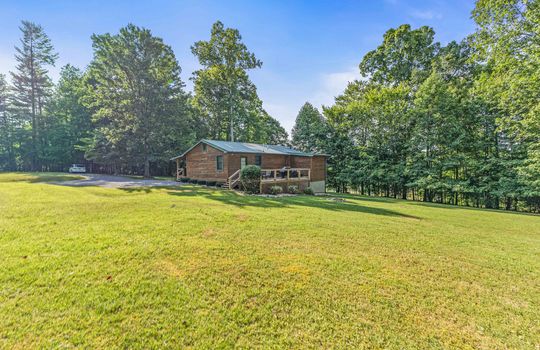 back view of home, back deck, back yard, log cabin, metal roof, yard, landscaping, trees