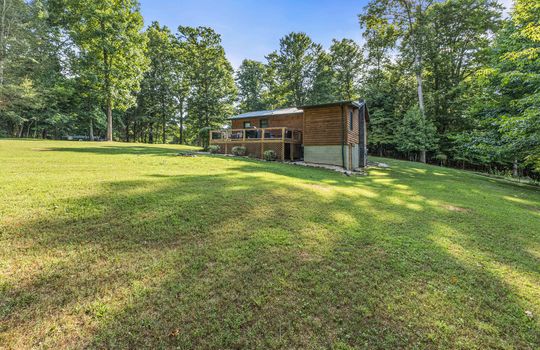 back view of home, back deck, back yard, log cabin, metal roof, yard, landscaping, trees